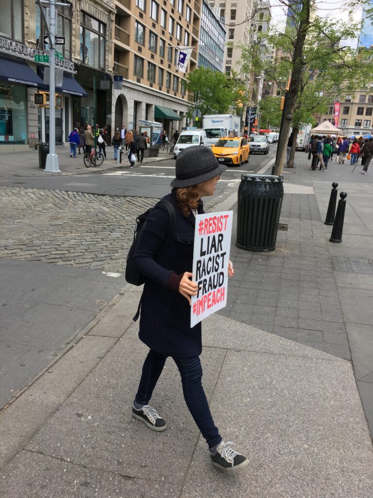 Janice walking on Union Square West with her protest sign