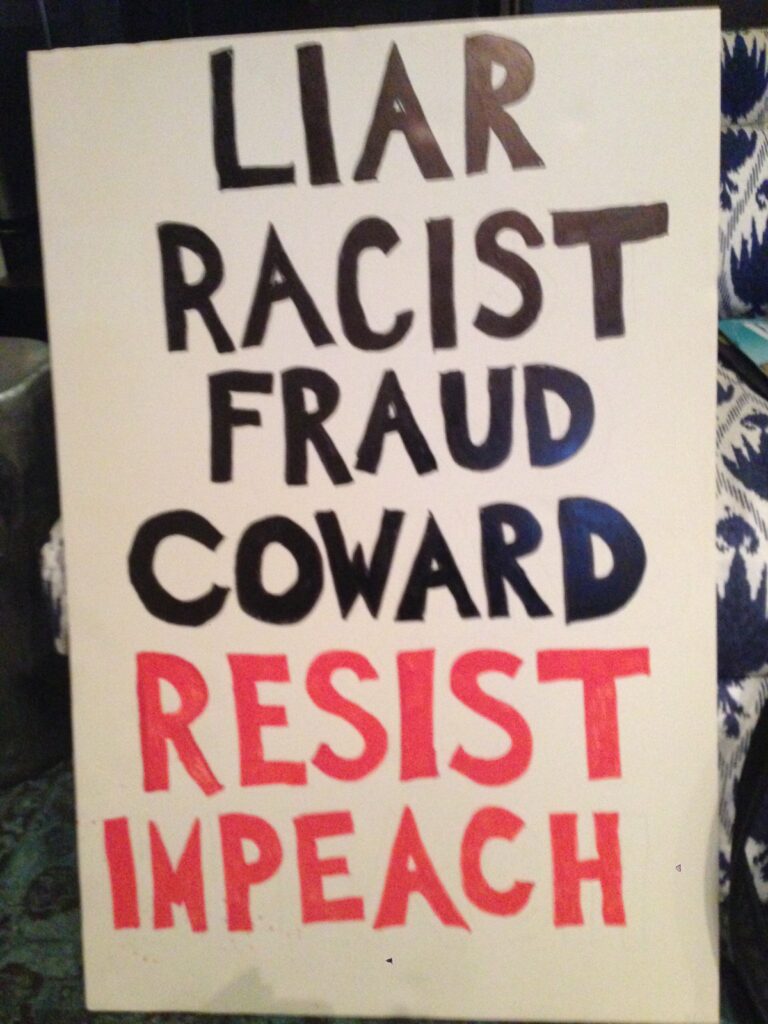 Protest sign reading LIAR RACIST FRAUD COWARD RESIST IMPEACH