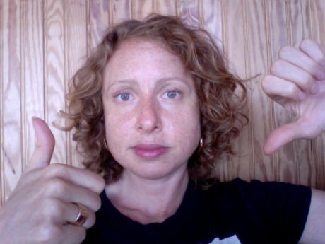 Janice holds up both hands, giving the "thumbs down" on one side and the "thumbs up" on the other side.