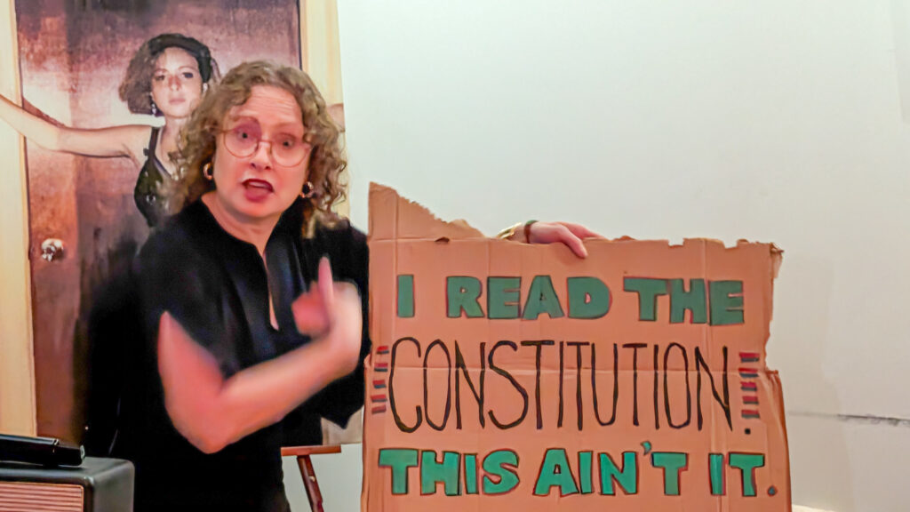 Janice holding No Kings protest sign reading I READ THE CONSTITUTION. THIS AIN'T IT.